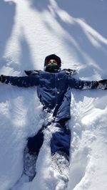 High angle view of boy lying on snow