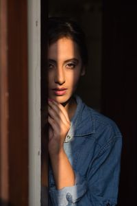 Portrait of beautiful young woman standing by window