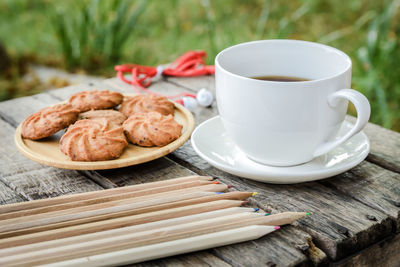 Close-up of coffee and cookies with pencils on table