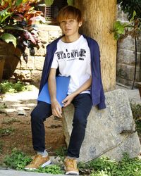 Young man standing against tree