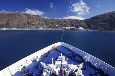 Men on boat deck in sea against sky