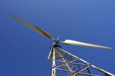 Low angle view of windmill against clear blue sky