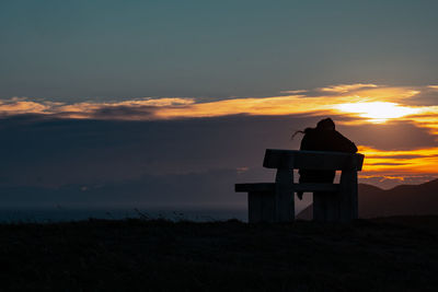 Silhouette built structure on field against sky during sunset