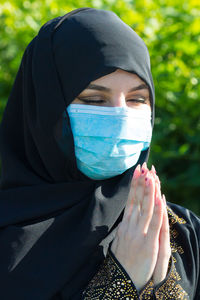 Close-up of woman wearing mask praying outdoors