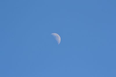 Low angle view of moon against clear blue sky