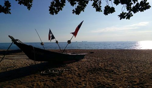 Ship moored on beach against sky