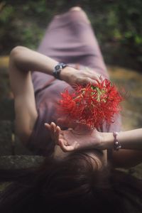 Midsection of woman holding red flower