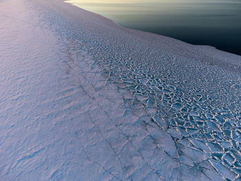 Snow-covered shore of the lake, cracked ice on the water. blocks of ice, folded into a huge mosaic.