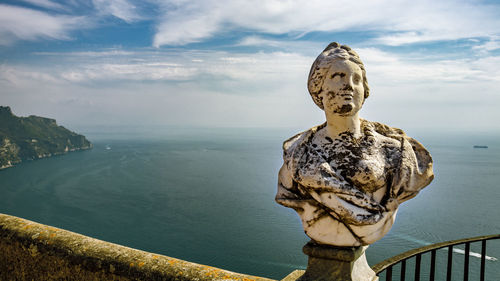 Statue by sea against sky