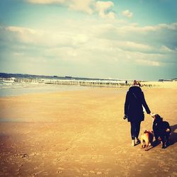 Rear view of man and woman at beach against sky