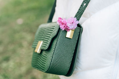 Close-up of pink japanese cherry blossoms in female green bag with imitation reptile skin.