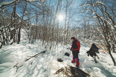 Man standing on snow against bare trees in forest