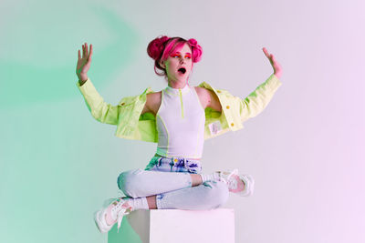 Portrait of smiling woman with arms raised standing against white background