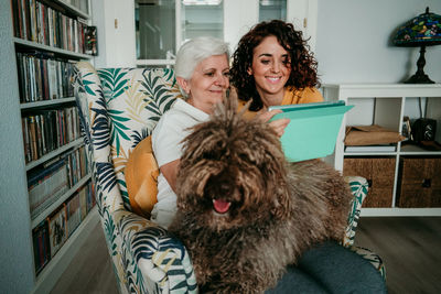 Mother and daughter looking at digital tablet while sitting with dog at home