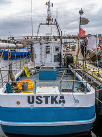 Fishing boats moored at harbor against sky