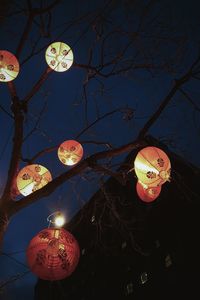 Low angle view of illuminated lanterns hanging against sky at night