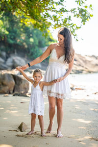 Full length of sisters standing on beach