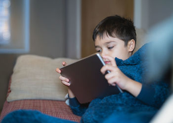 Happy kid watching cartoon on tablet,  cute boy playing game online with friends on internet