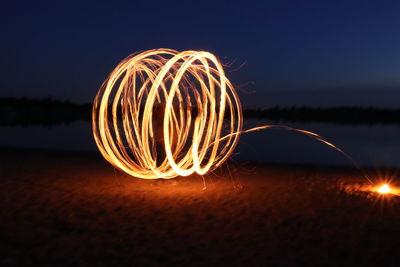 Close-up of illuminated lights on beach against sky at night