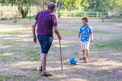 Grandfather and grandson playing football in the park