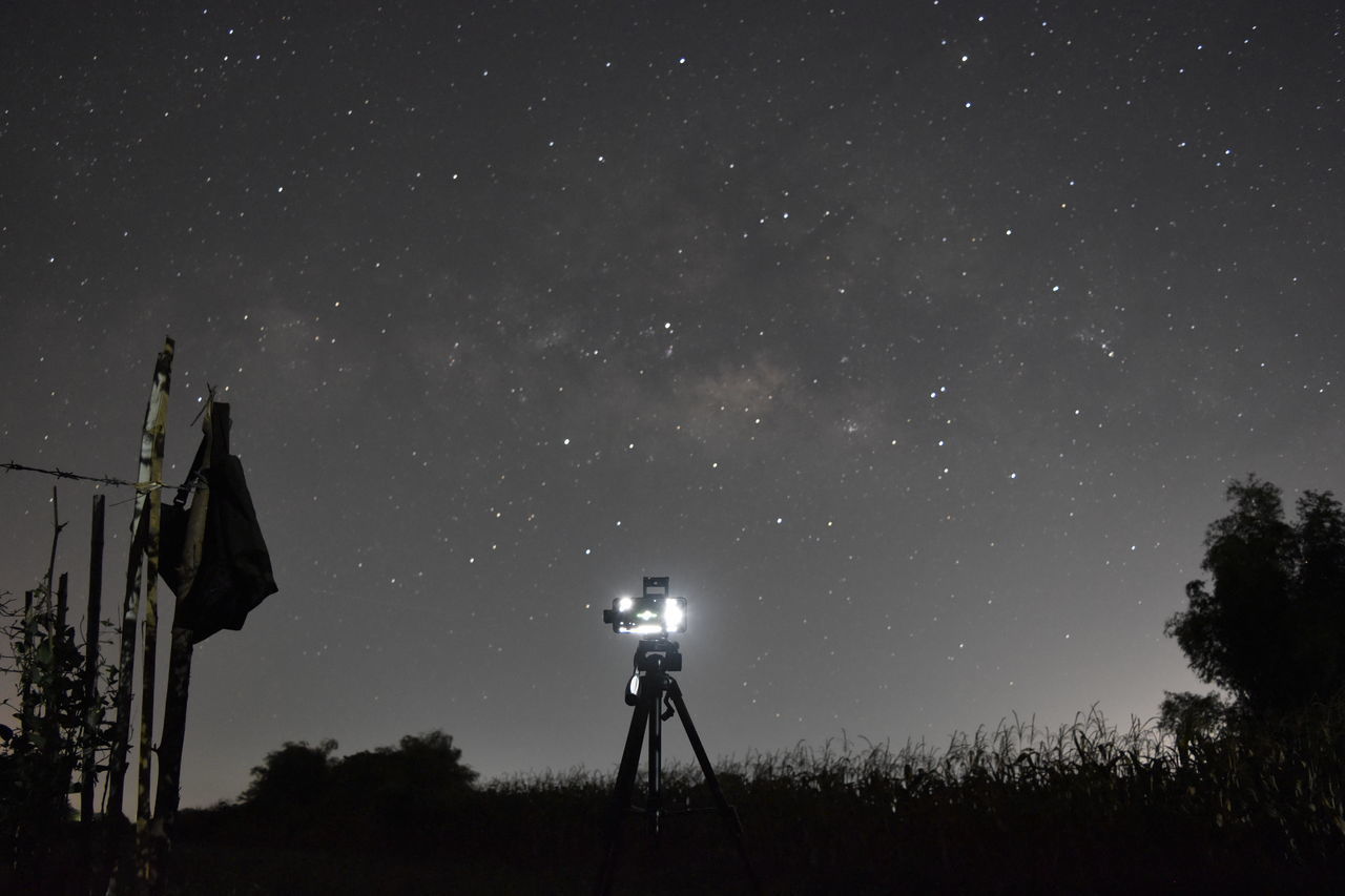 SILHOUETTE MAN PHOTOGRAPHING ILLUMINATED AGAINST STAR FIELD