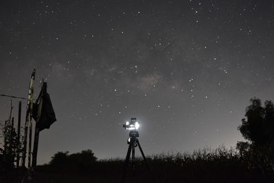 Silhouette man photographing illuminated against star field at night