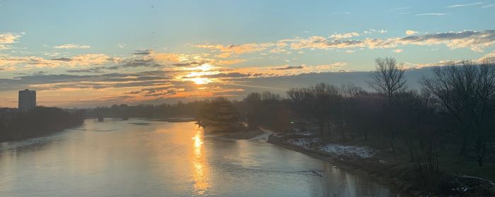 Scenic view of river against sky at sunset