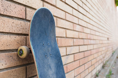 Skateboard supported on a brick wall.