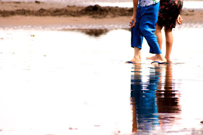 Low section of man and woman walking on shore at beach