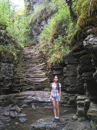 Portrait of woman standing on rocks in lake at forest