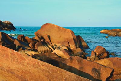 Scenic view of rocks on beach against clear sky