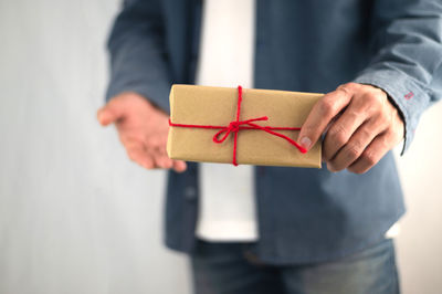 Midsection of man holding paper while standing against wall