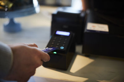 Cropped image of customer paying through credit card at checkout counter in cafe