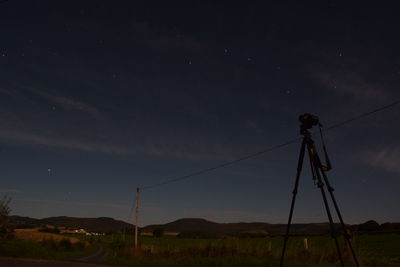 Electricity pylon on field against sky at night