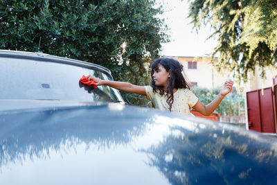 Girl washing blue car in the garden