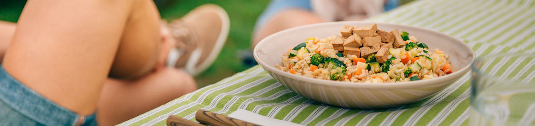 Low section of woman sitting by food on table