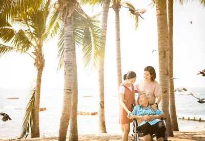 People sitting on palm tree at beach
