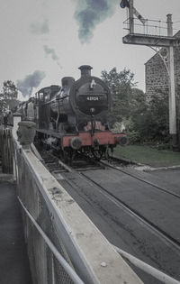 Train at railroad station in city against sky