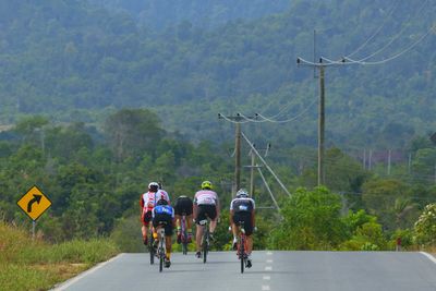 Rear view of people riding bicycle on road