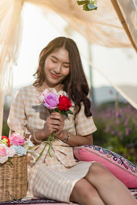 Beautiful young woman sitting on sofa by potted plant