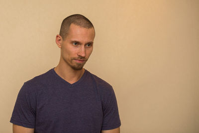 Portrait of young man standing against wall