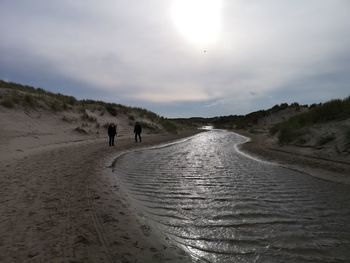 People walking on beach against sky