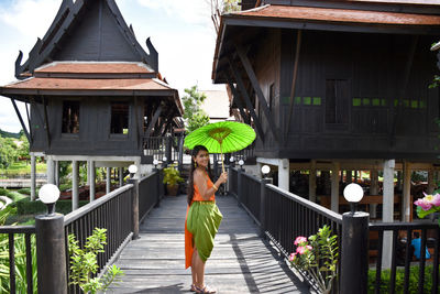 Rear view of woman walking on footbridge amidst buildings