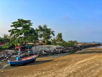 Boat moored on beach against clear sky