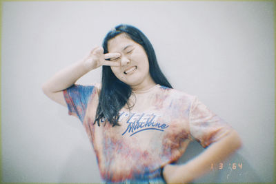 Portrait of smiling young woman standing against wall