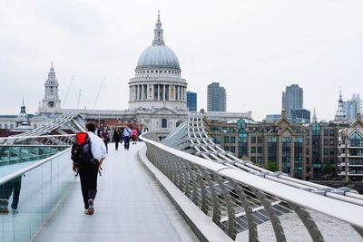 People walking on london millennium footbridge against st paul cathedral