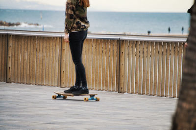 Low section of woman skateboarding on promenade