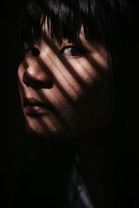 Close-up portrait of young woman in dark