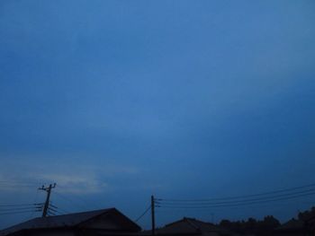 Low angle view of silhouette roof against blue sky