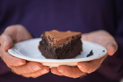 Midsection of man holding chocolate cake in plate